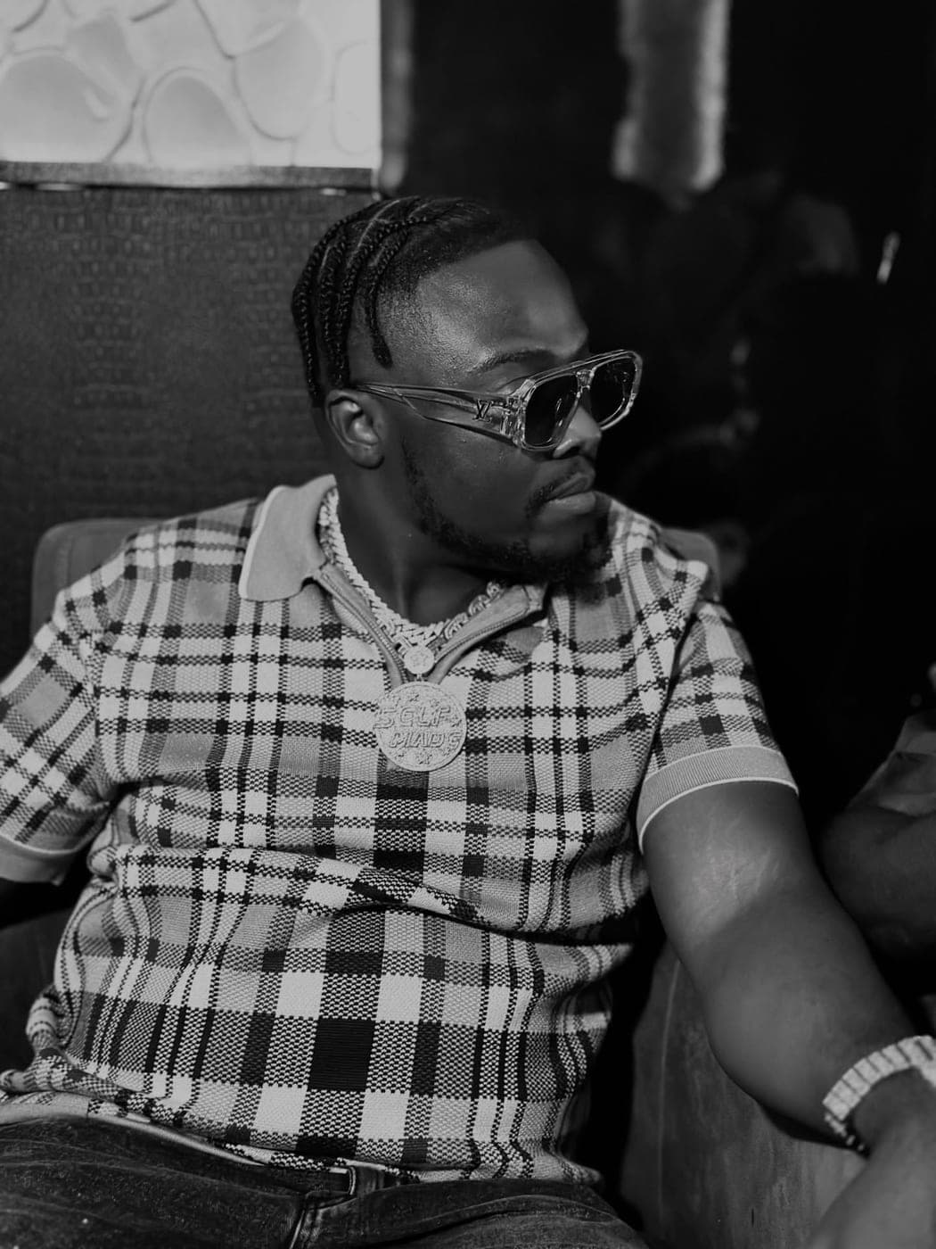 King Kaly in a black-and-white portrait wearing sunglasses and a chain