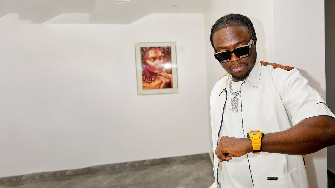 King Kaly in white, checking a yellow watch